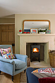 Light blue armchair with lit woodburner in Gloucestershire cottage UK