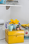 Cut flowers and novelty cups on yellow cabinet in Brighouse kitchen West Yorkshire UK