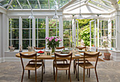 Wooden dining table and chairs in conservatory extension of London townhouse UK