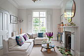 White corner sofa with cut flowers on coffee table in living room of London townhouse UK