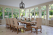 Cream dining chairs at table for ten in Kent conservatory England UK