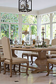 Cream dining chairs at table in Kent conservatory with fanlight windows England UK