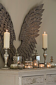Lit candles and silverware with angel wings on sideboard in Kent country house England UK