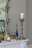 Lit candles and perfume bottles with mirror on shelf in Kent country house England UK