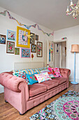 Verschiedene Kissen und Kunstwerke auf einem rosa Sofa mit Knöpfen im Wohnzimmer von Kidderminster, Worcestershire, England UK