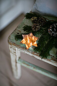 Lit candles with pinecones on old chair in Cheshire home UK