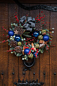 Blue baubles and cinnamon sticks in Christmas wreath on wooden front door of Berkshire home UK
