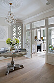 Chandelier above hall table with books in double reception of London townhouse UK