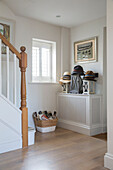 Sunhats and lanterns with footwear in basket in hallway of West Sussex home