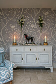 Lit candles on upcycled sideboard with floral wallpaper in Dorset farmhouse UK