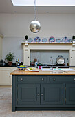 Silver pendant light above teal workbench in Dorset farmhouse kitchen UK