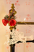 Red Christmas bells and angel playing trumpet on bed frame in Georgian cottage Liverpool UK