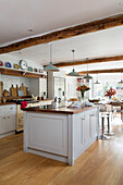 Pendant lights hang above white island unit in open plan kitchen of Oast house conversion Kent UK