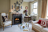 Gilt armchair and lamps at fireside with decorative mirror in London townhouse UK