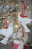 Two white doves hang in silver Christmas decorations London townhouse UK