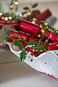 Metallic red crackers with holly and berries in London townhouse UK