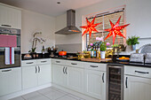 Two lit stars with stainless steel extractor and oven in white fitted kitchen of London townhouse UK