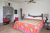 bright floral cover on double bed with geometric patterned fireplace in Italian villa Amalfi Southwest