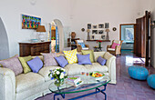 Lilac cushions on curved sofa with glass topped coffee table in living room of Italian villa on the Amalfi coast