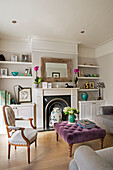 Grauer Sessel mit lila Ottomane im Wohnzimmer eines Londoner Hauses UK
