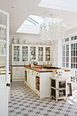 Chandelier below skylight in spacious white fitted kitchen of Edwardian house Surrey UK