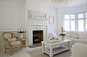 Cream armchair at fireside with bay window in white Edwardian living room Surrey UK