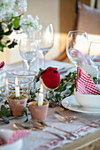 Gingham napkin and red robin with lit candles on dining table in West Sussex farmhouse UK