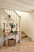 Pair of candlesticks and large star decoration on side table with crate in staircase of West Sussex farmhouse UK