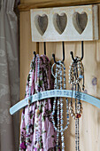 Pink scarf and clothes hanger with beaded necklaces on heart hook in Alford home Surrey UK