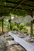 Paper shades over pergola dining table with seat cushions in Alford garden Surrey UK