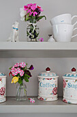 Cut flowers and chinaware with dog ornament on shelves in Alford kitchen Surrey UK