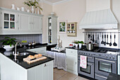 Light green and black fitted kitchen with range oven in West Sussex townhouse UK