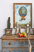 Gilt framed hot air balloon with fruit and candles on ageing chest of drawers in South London schoolhouse conversion UK