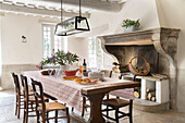 Modern glass lampshade above dining table with original fireplace in 19th century Provencal farmhouse France