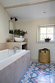 Blaue und rote Bodenfliesen mit Badewanne und Wäschekorb in einem provenzalischen Bauernhaus aus dem 19