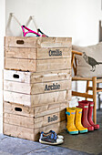 Stiefel und Kisten mit Namen von Jungen in einer umgebauten Scheune in Gloucestershire, England