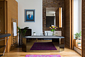 Large mirror on exposed brick wall with black freestanding bath in Victorian London townhouse UK