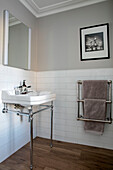Black and white print above towel rail with washstand and mirror in London home UK