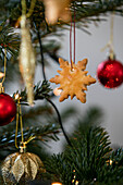 Schneeflockenbaumschmuck mit roten und goldenen Kugeln am Weihnachtsbaum in West Sussex, Großbritannien