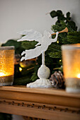 Angel and lit candles on wooden Arts and Crafts mantlepiece West Sussex UK