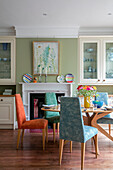 Verschiedene Stühle am Tisch in einem hellgrünen Esszimmer mit Glasvitrinen in einem Haus im Arts and Crafts-Stil in Sevenoaks, Kent, Großbritannien