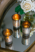 Vintage tealights on mirrored tray with single white rose in Hampshire home
