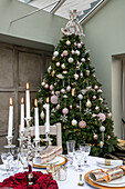 Beleuchtete Kerzen auf einem Esstisch mit großem Weihnachtsbaum in einem Haus in Hampshire