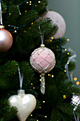 Pastel pink baubles and white ceramic hears hang on Hampshire Christmas tree