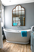 Vintage mirror above freestanding bath in Hampshire home