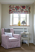 Pink armchair with floral blinds at window in Somerset farmhouse UK