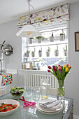 Cut tulips on table with salad and container plants hung in window of Victorian terrace London UK
