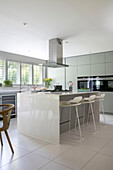 Spacious modern kitchen with bar stools and wooden chairs in Surrey home UK