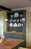 Plates and glasses on dark green kitchen dresser in Somerset home UK