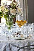 Cut flowers on dining table with cut glass at place setting in Devon home UK